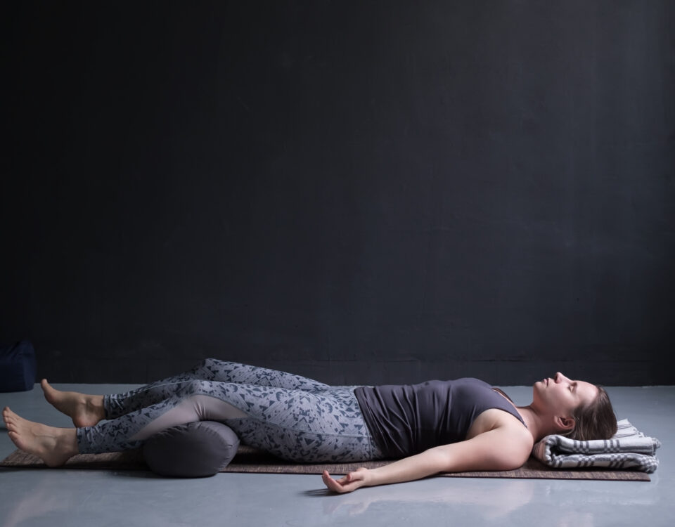Femme pratiquant une pose de yoga avec un bolster pour le soutien