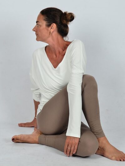 Woman dressed in tight beige pants and a navy blue long-sleeve top with a lovely back neckline.