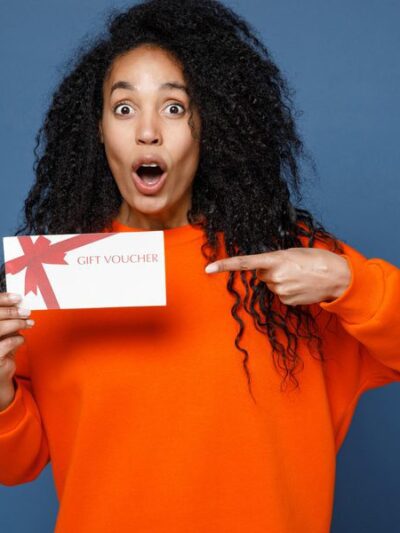 Femme surprise tenant un bon cadeau.