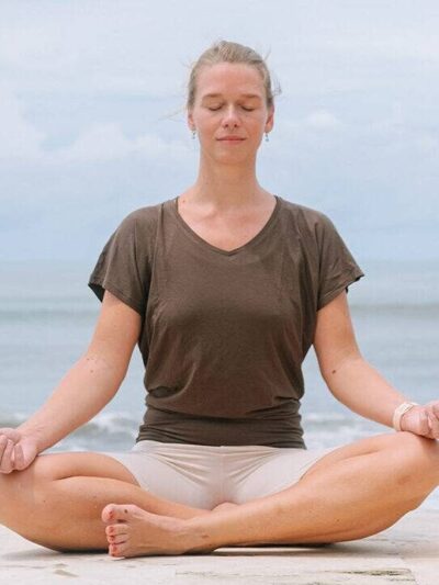 Woman meditating in lotus position on the beach.
