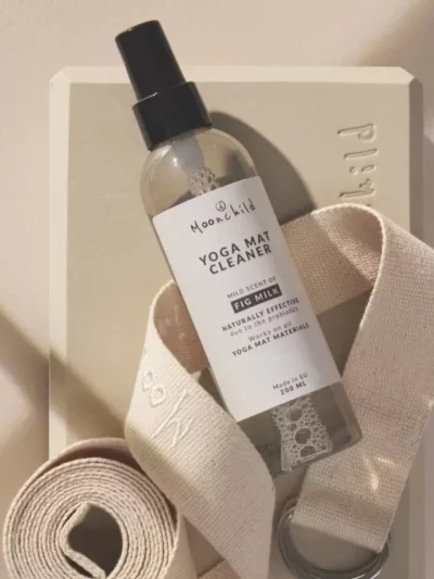 Transparent Moonchild fig milk yoga mat cleaning spray placed on a yoga block and a yoga strap