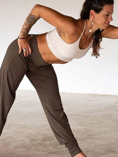 Yogini in triangle pose wearing loose pants tapered at the ankles and hips, and an ecru bandeau bra