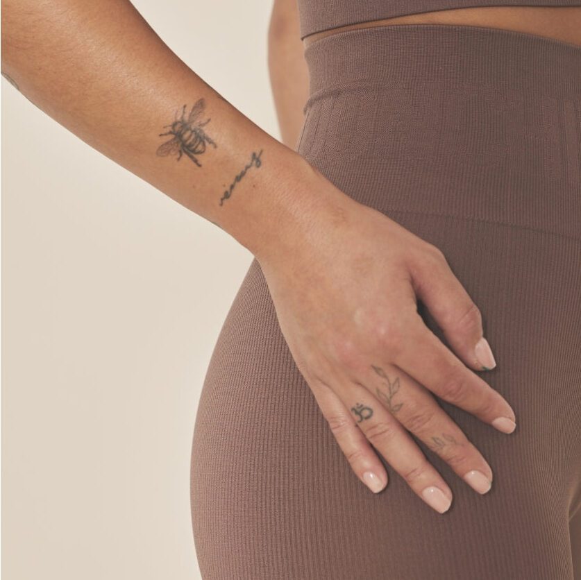 Hand with tattoos on brown sportswear
