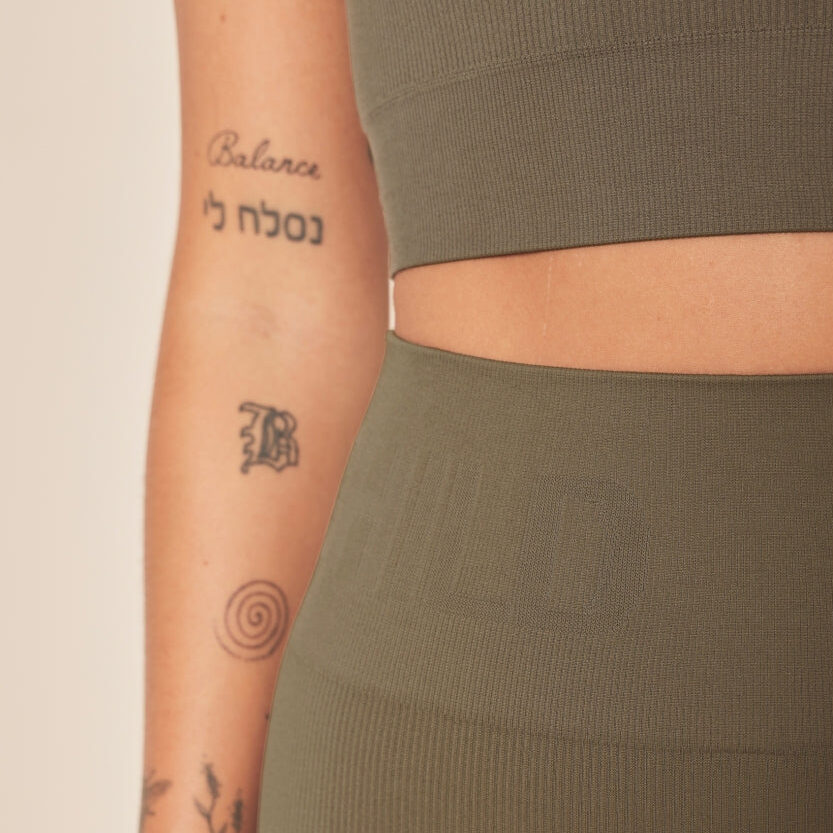 Green sportswear with visible arm tattoos