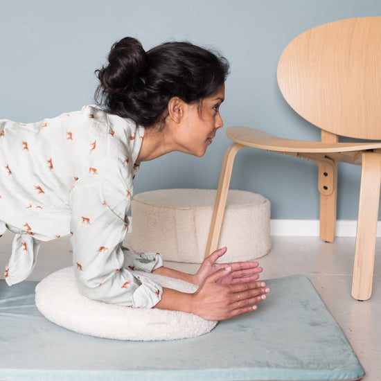 Woman practicing yoga on cushions at home