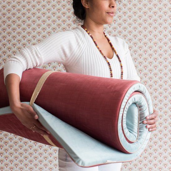 Person carrying a large red yoga mat