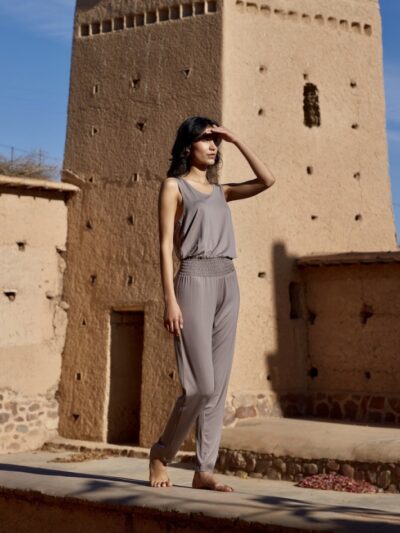 Woman wearing a lightweight fabric jumpsuit with a cinched waist in sand beige color