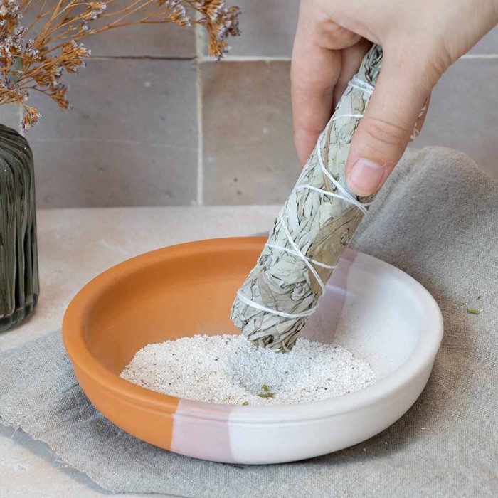 White sage bundle stick lit over an incense plate