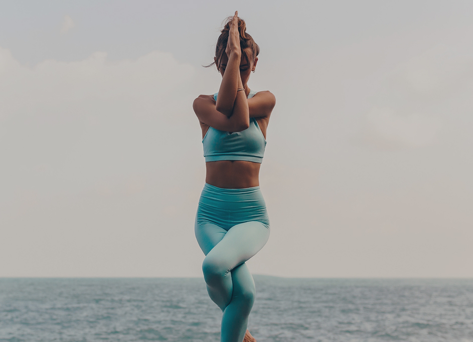 une femme gracieuse pratique le yoga sur des rochers dans les habits Yoga Nest
