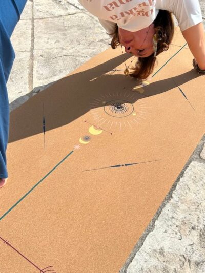 Woman in downward dog on cork yoga mat with colorful centered patterns by French brand Yogom