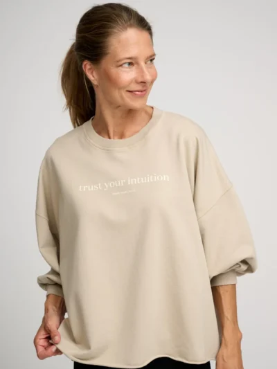 Woman wearing a beige sweatshirt with a positive message