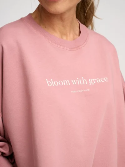 Woman wearing a pink sweatshirt with ¾ puff sleeves and printed message on the front