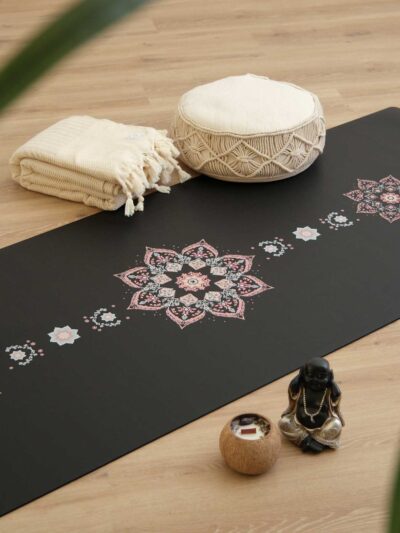 Tapis de yoga noir avec des motifs de mosaïque florale inspirée d'Orient, dans une ambiance de pratqiue de yoga avec des coussins de méditation et des bougies