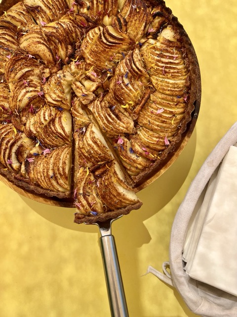 Sliced apple tart on a yellow background.